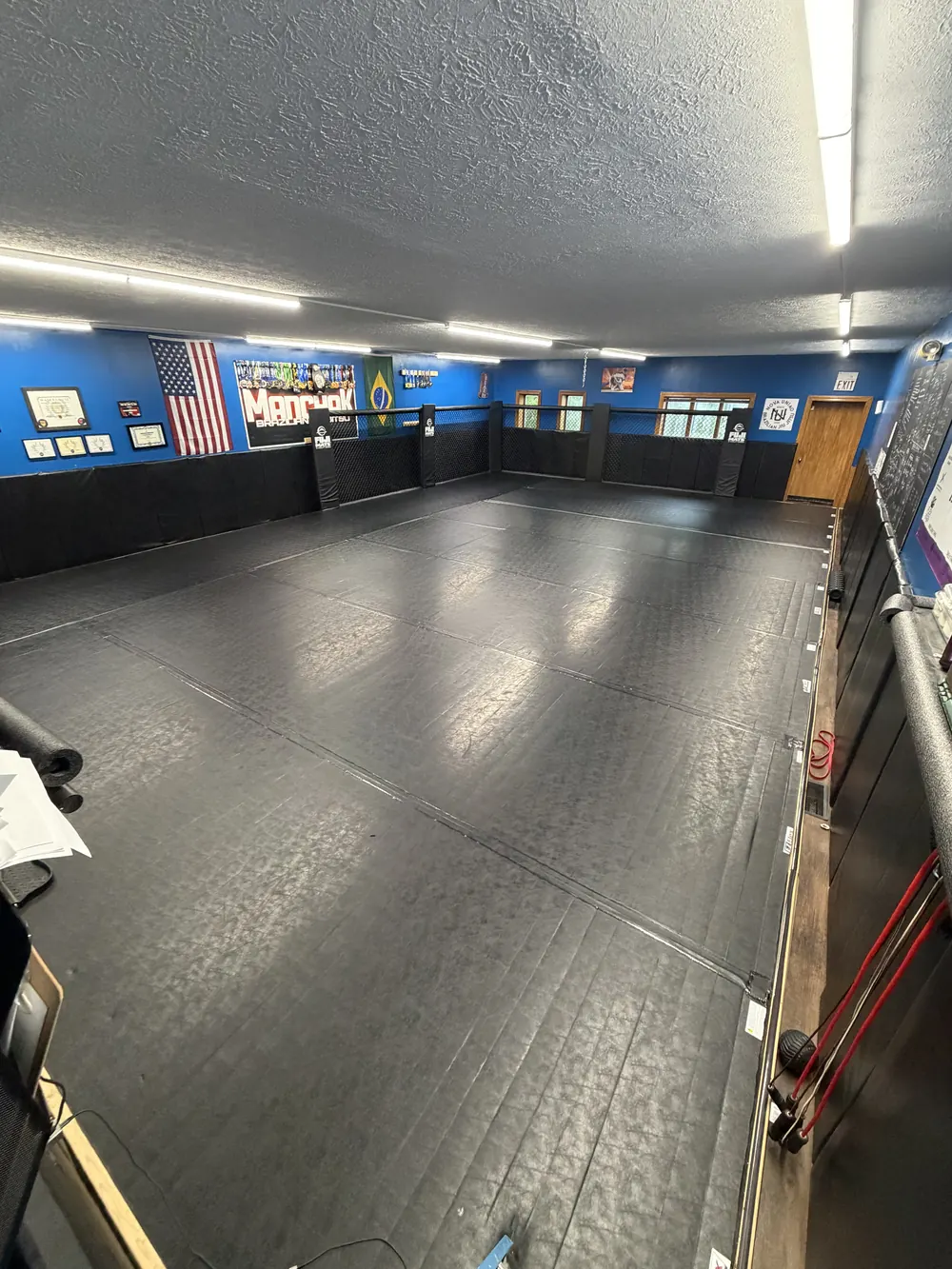 Mats, flags and the blue walls of the Jiu Jitsu room at Legacy Gym